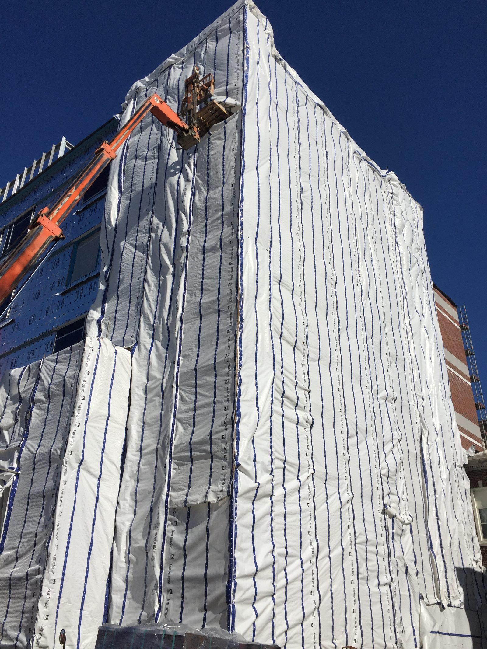 Multi-story building wrapped in flame-retardant enclosure sheeting for winter work